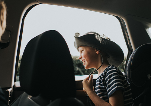 criança junto a janela aberta de um carro