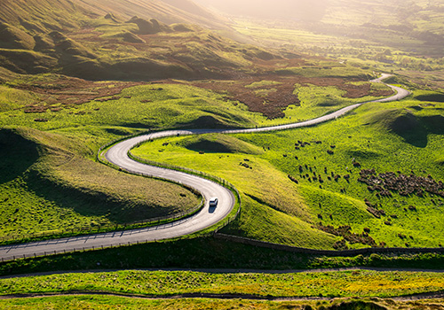 Carro entre as montanhas num dia de sol.
