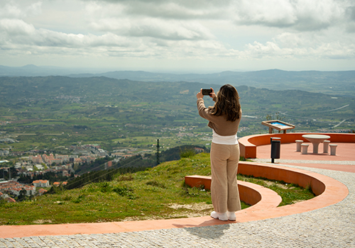Turista a tirar foto de um miradouro na Serra da Estrela.