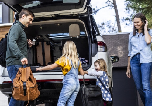 família a carregar malas para viagem longa de carro